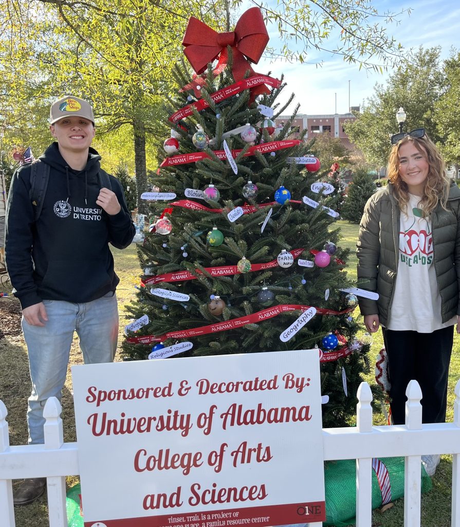 Ambassadors next to the College's tree at a local event